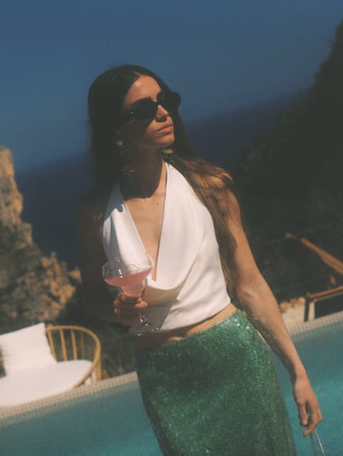 Escena de mujer con una copa junto a piscina